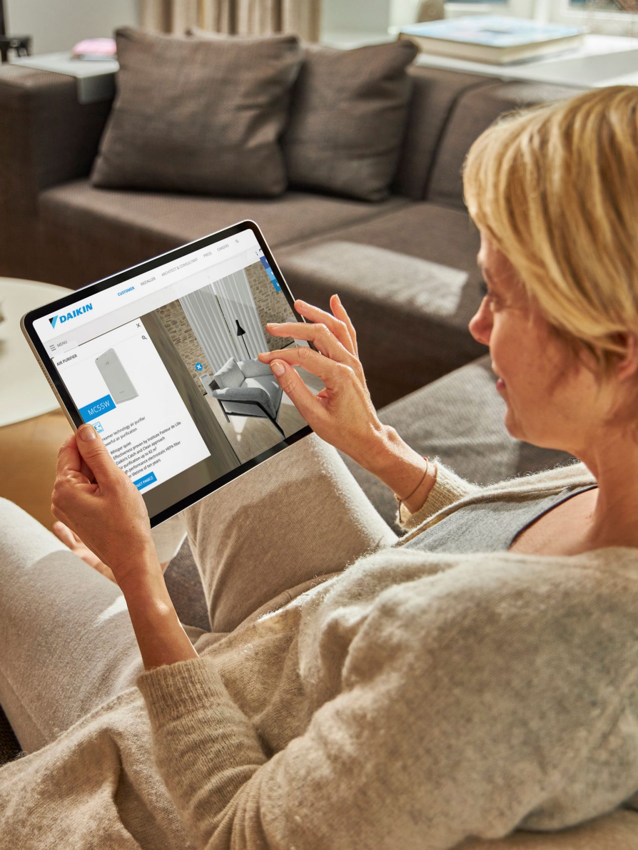 Una donna seduta sul divano guarda i climatizzatori nel centro di esperienza virtuale sul suo tablet